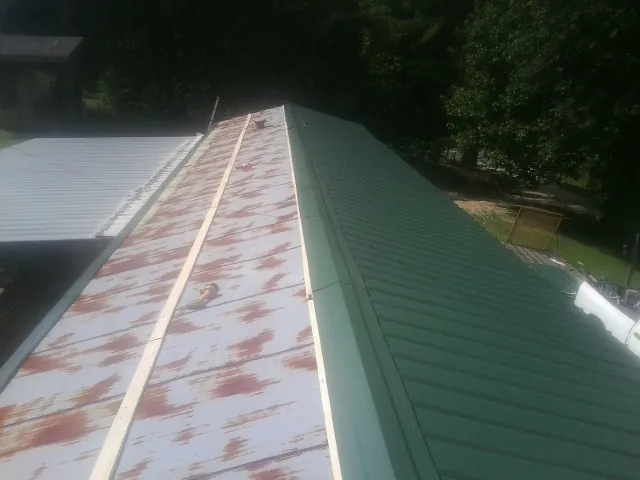 Old rusted panels beside newly installed green metal roofing — Wind Damage Roof Repair by Roofing Brothers in Rutherford