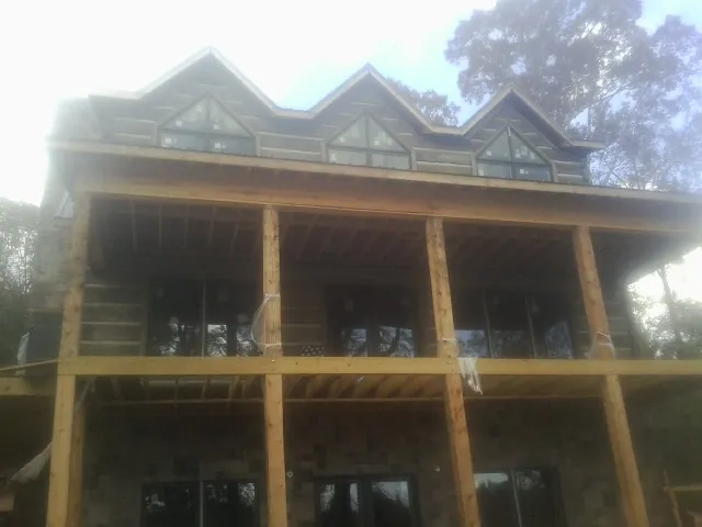 Dormers and porch framing on a large log home under construction — Roof Coating work by our crew in Rutherford