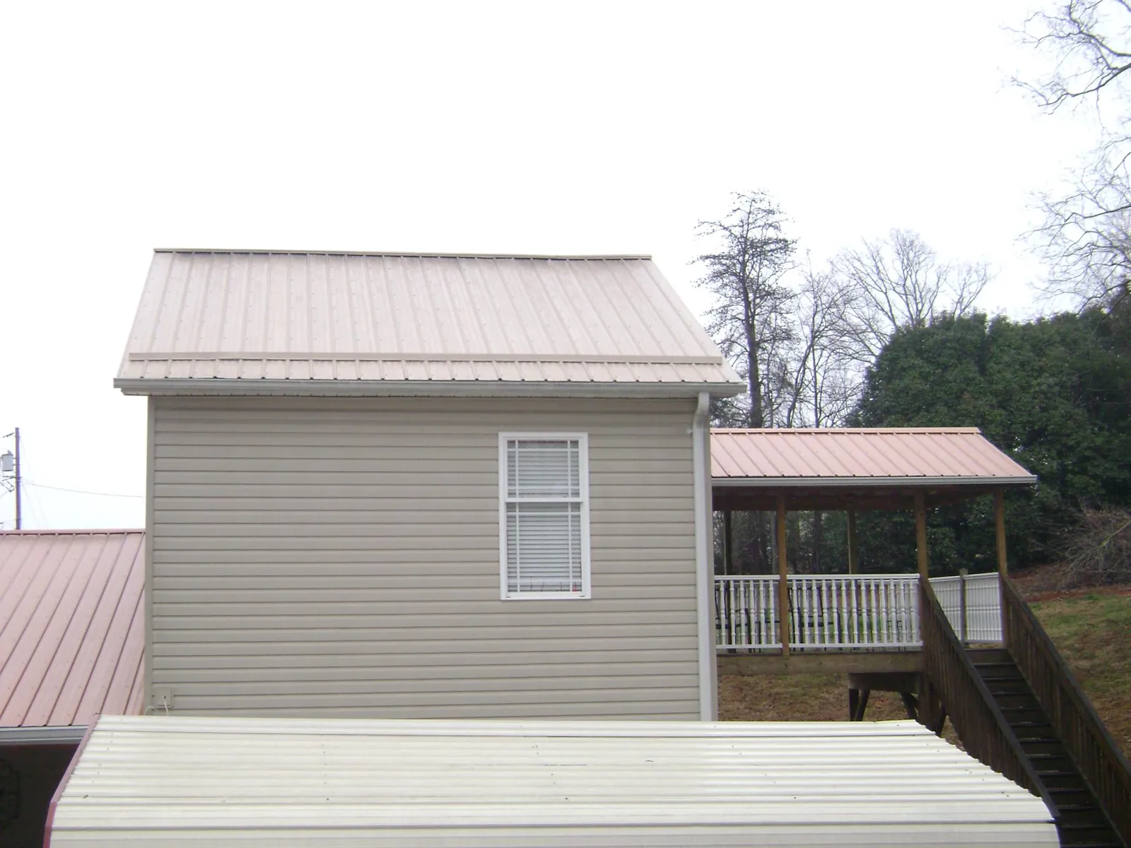 Tan metal roofs on a two story addition and attached porch, from a Roof Replacement job in Rutherford